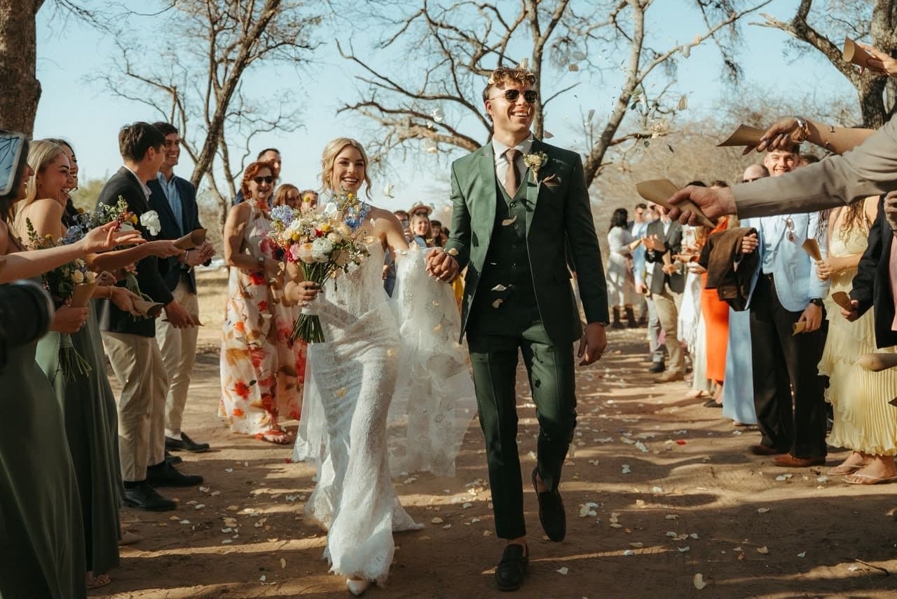 Emma and Juan walk out through their guests in a shower of confetti